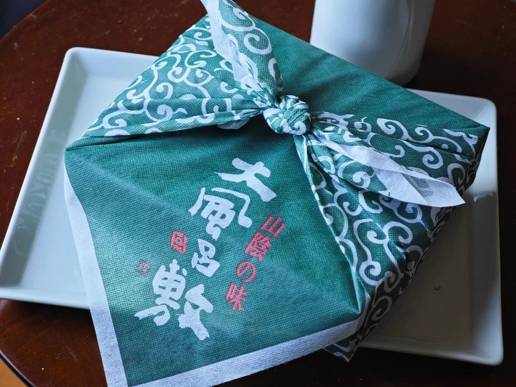 Oburoshiki gift box tied in its green furoshiki-style cloth