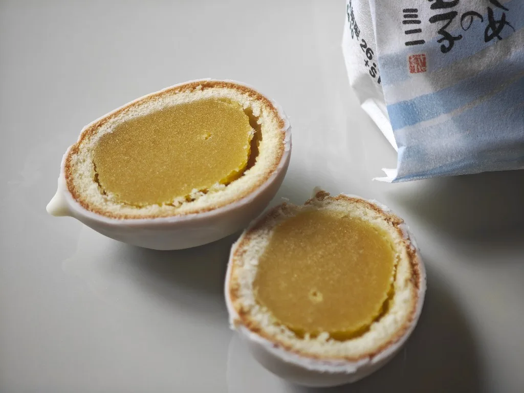 Two halves of Kamome no Tamago Mini showing white chocolate, sponge, and yellow bean paste