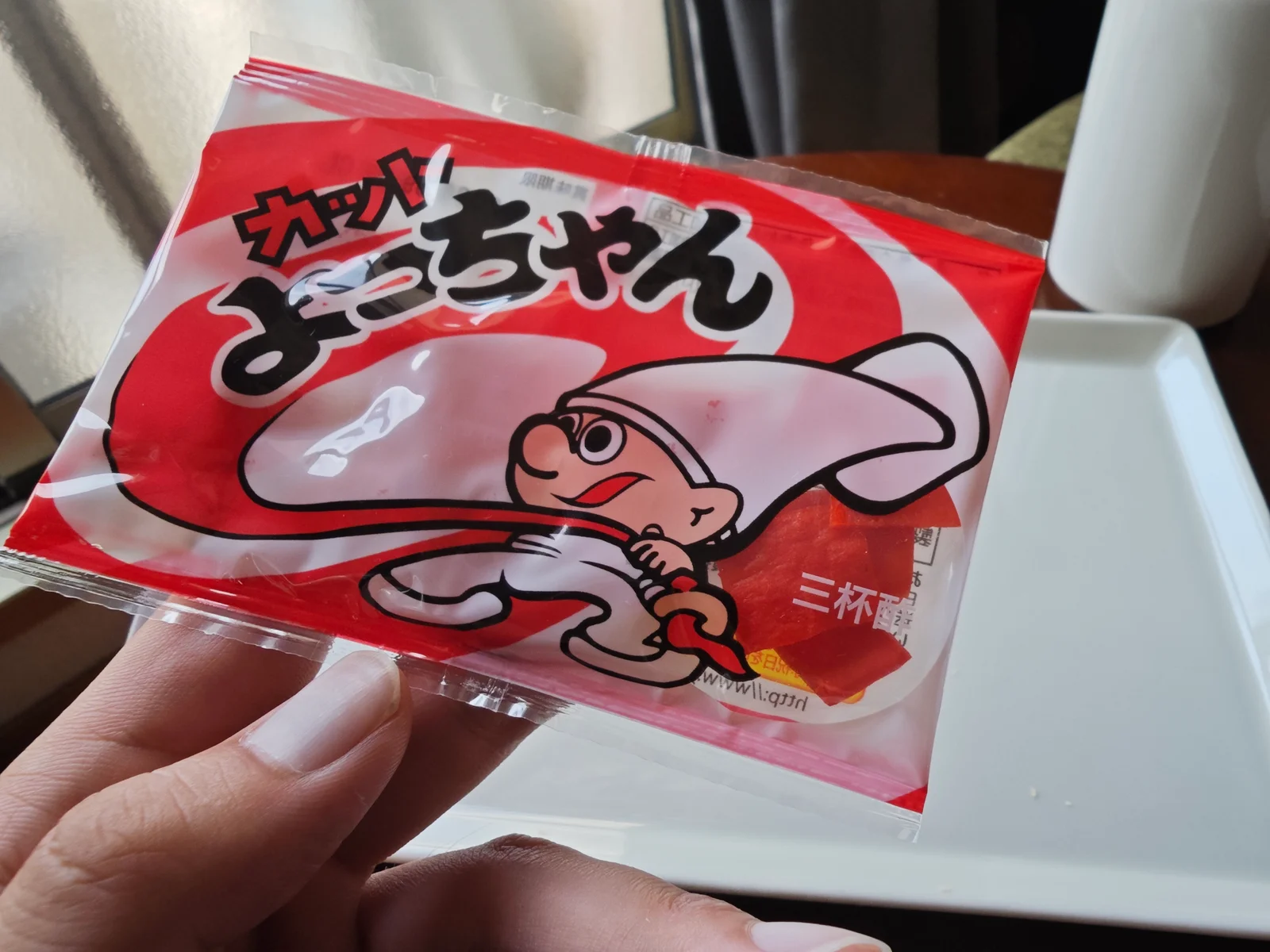 Hand holding a classic red Cut Yocchan pack with the brand mascot centered