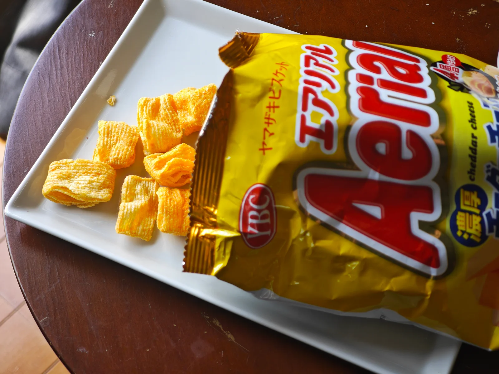 Opened YBC Aerial Rich Cheddar bag with cheese pieces spilling onto a plate