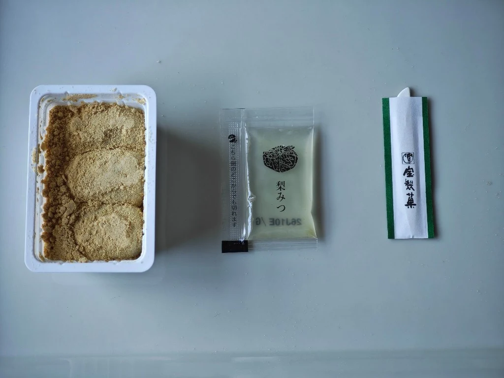 Kinako mochi, pear syrup packet, and eating pick arranged as one serving