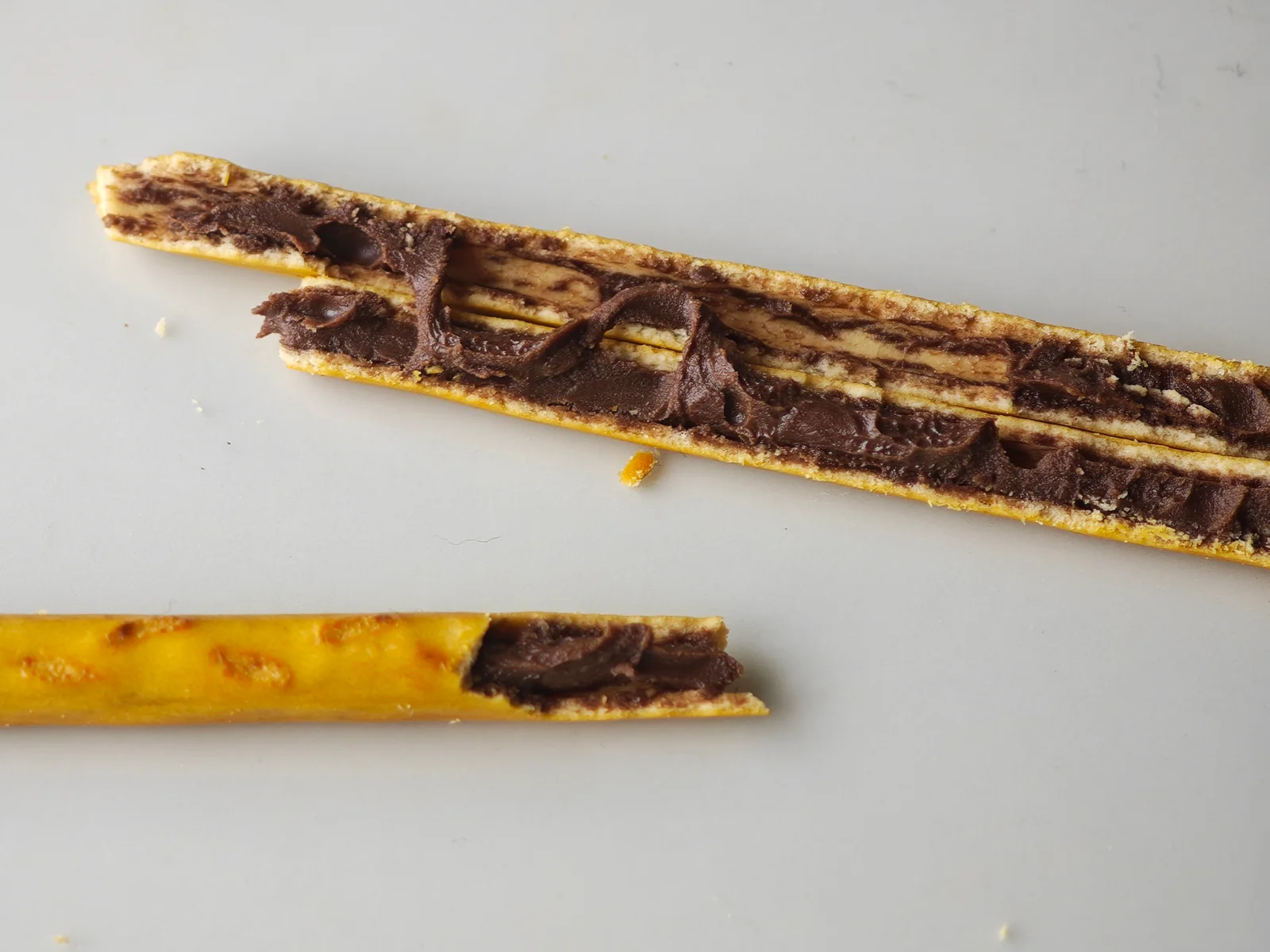 Lengthwise-split Toppo stick showing chocolate filling from end to end