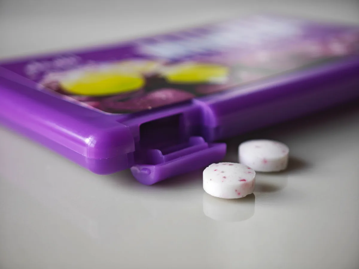 Two MINTIA Grape tablets beside the purple case