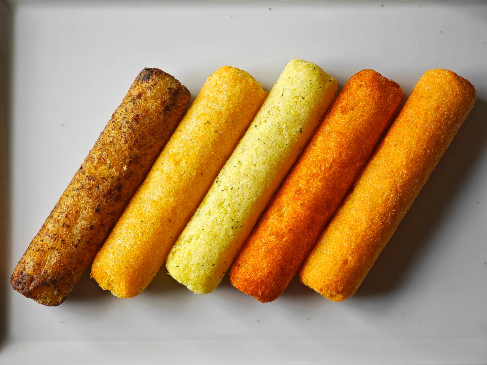Five unwrapped Umaibo flavors arranged on a plate