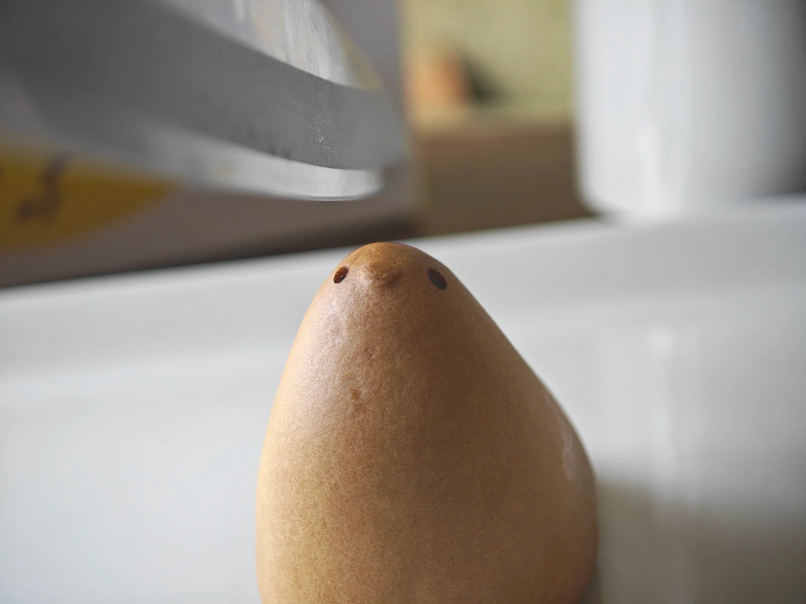 A kitchen knife poised above Hiyoko before the sweet is cut for a cross-section