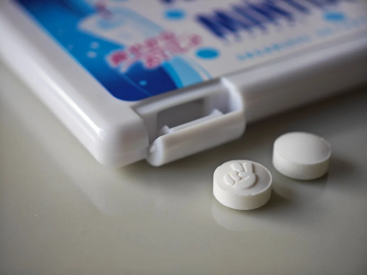 Two Calpis MINTIA tablets, one embossed with a design