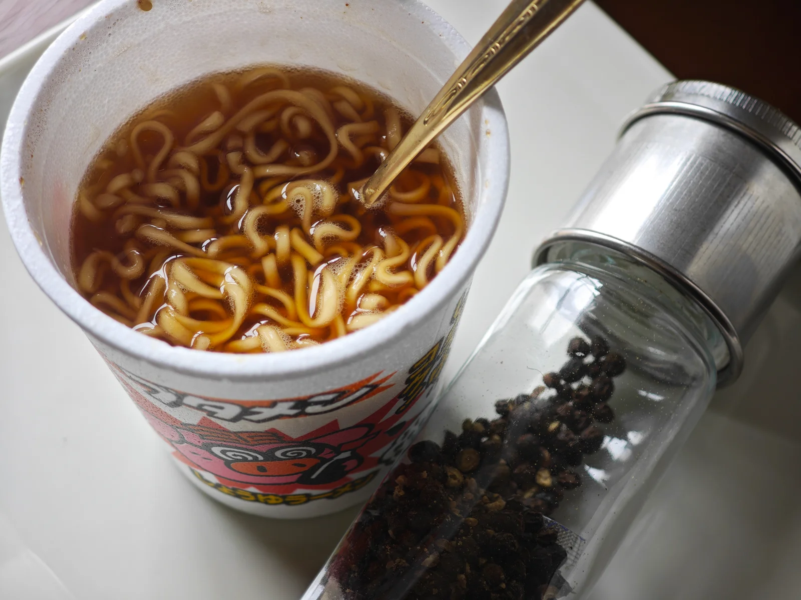 Shoyu Butamen beside a black-pepper grinder