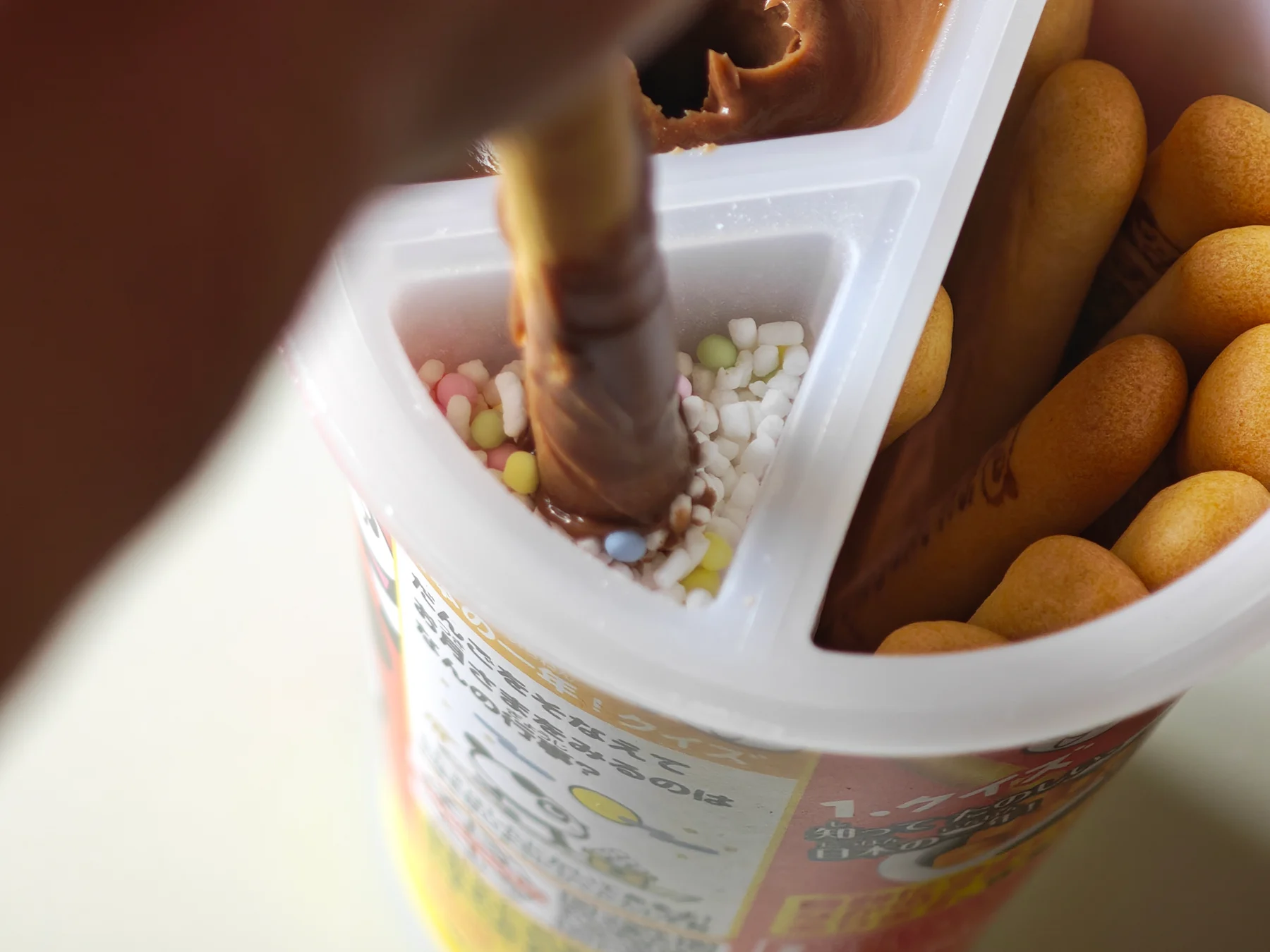 A chocolate-coated cracker pressed directly into the topping compartment