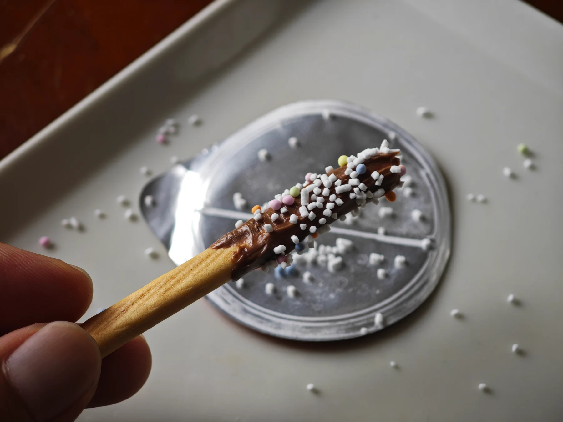 Chocolate-coated Yan Yan stick sprinkled over the opened foil lid