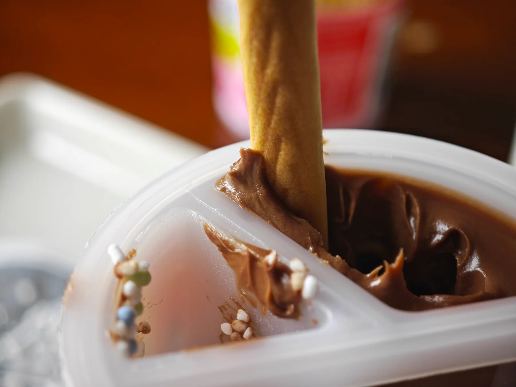 A Yan Yan cracker rolling against the rim of the chocolate compartment