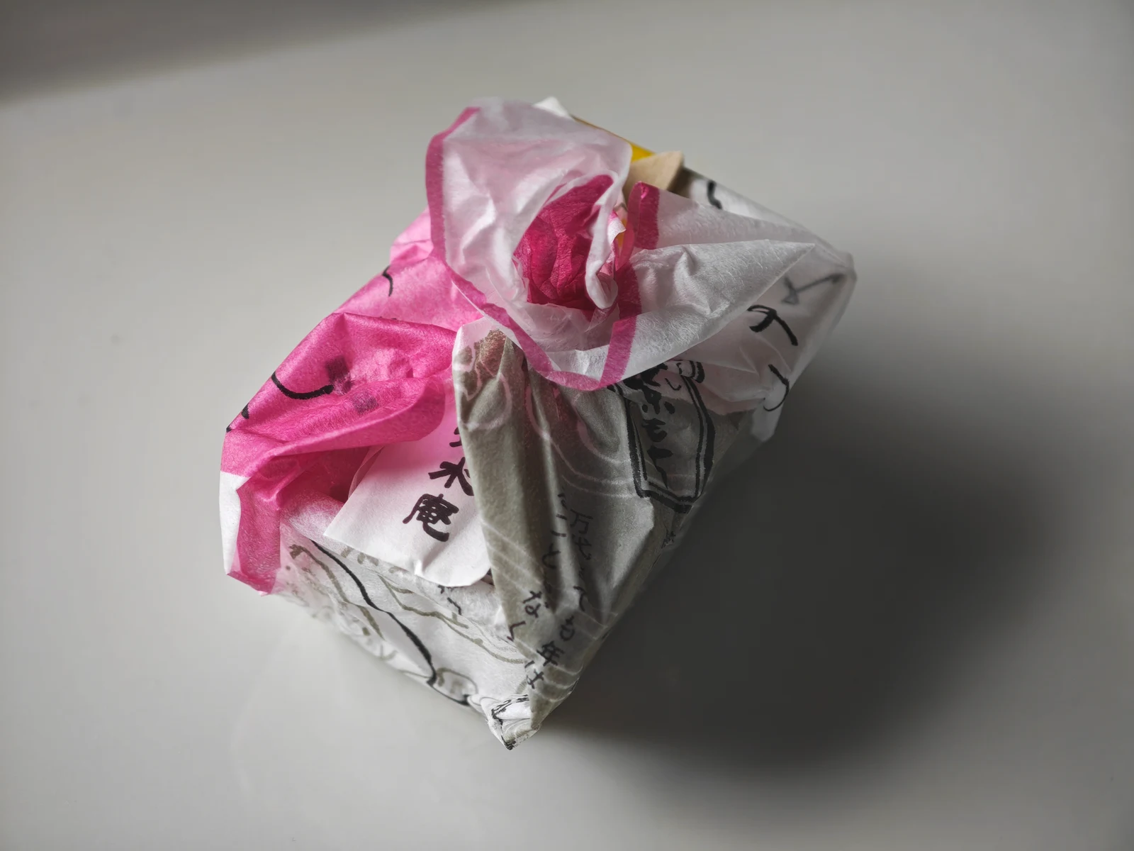 One Tsukushi Mochi serving in its pink and white furoshiki-style wrapper