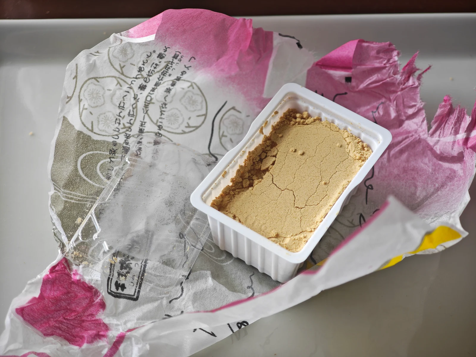 Tsukushi Mochi tray opened on top of its wrapper to catch loose kinako