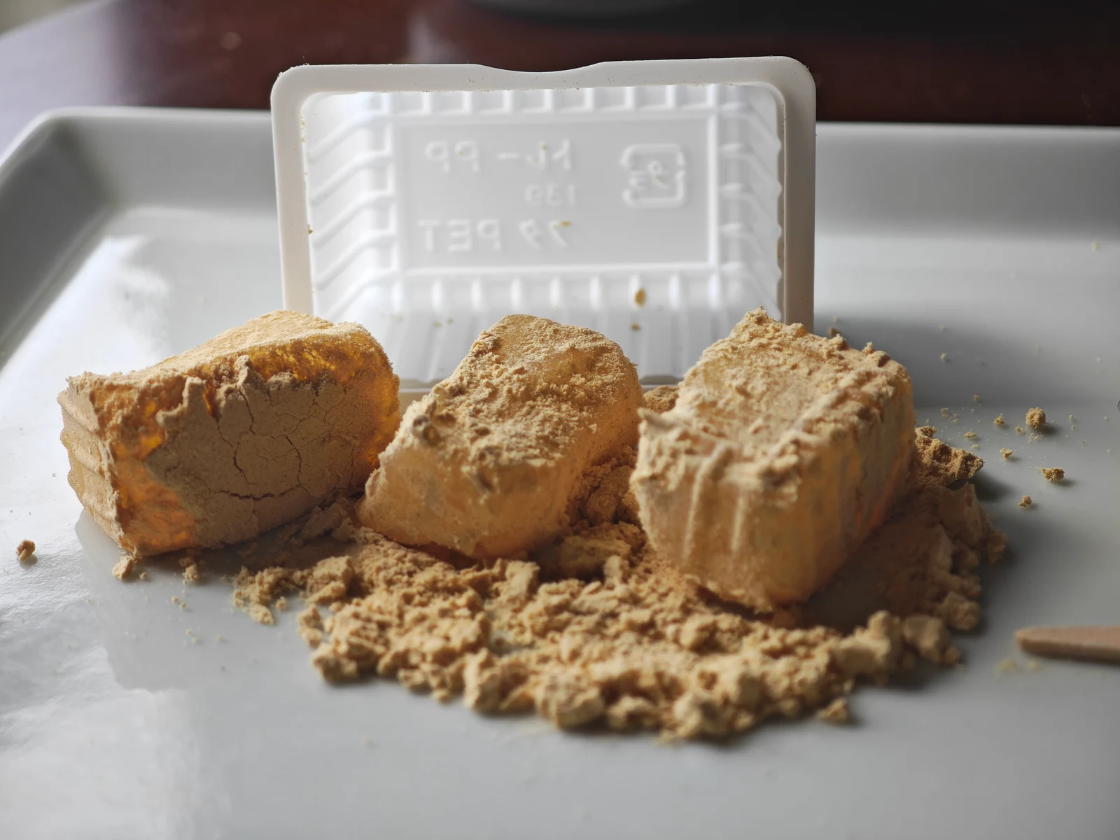 Three pieces of Tsukushi Mochi placed on a plate to show their shape and kinako coating