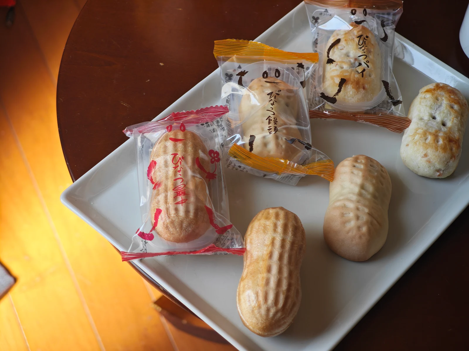 Wrapped and unwrapped Peanut Monaka, Peanut Manju, and Peanut Pie arranged on a white tray