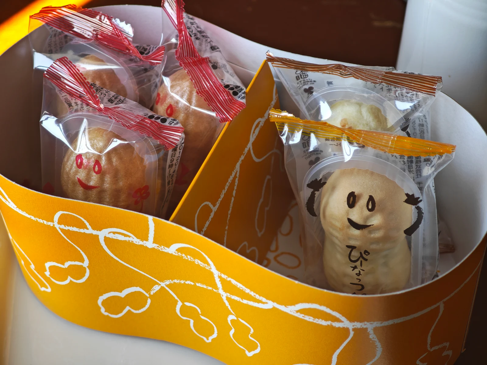 Half-eaten Chiba Meguri box with Peanut Monaka and Peanut Manju wrappers whose faces peek over the edge